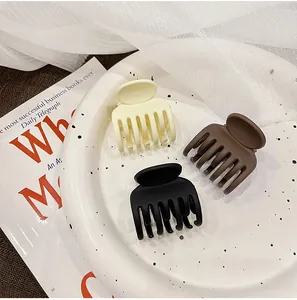 Three minimalist matte hair claws in beige, coffee, and black on a decorative white plate