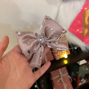 Dettaglio del fermaglio a fiocco rosa con strass a cuore e cristalli scintillanti