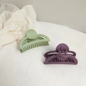Detailed macro view of sage green and purple matte resin hair claws on white fabric