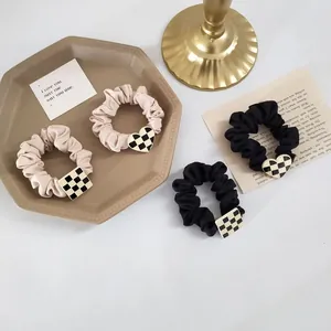 Detail of satin scrunchies with black and white checkerboard heart and square charms