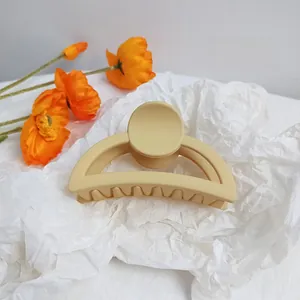 Close-up of a matte beige cream hair claw clip with orange floral decorative accents