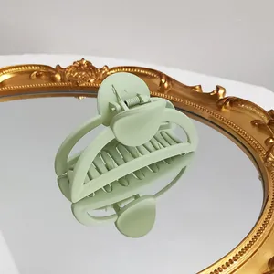 Macro shot of mint green matte hair claw clip on vintage mirror with textured surface
