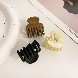 Three matte hair clips in brown, cream, and black displayed on a stylish ceramic tray