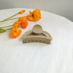 Macro shot of a matte khaki hair claw clip on a white background with orange flowers