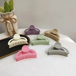 Close-up of matte large hair claws in pastel colors on a soft white fabric surface