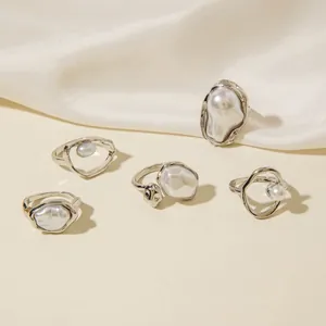 Detail eines fünfteiligen Silberring-Sets mit Barockperlen auf weißer Seide
