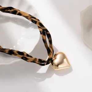 Dettaglio del cordoncino leopardato in tessuto e del grande ciondolo a cuore dorato