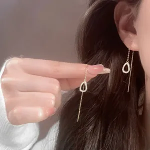 Detail of gold drop-shaped dangle earrings with sparkling stones on elegant ear threads