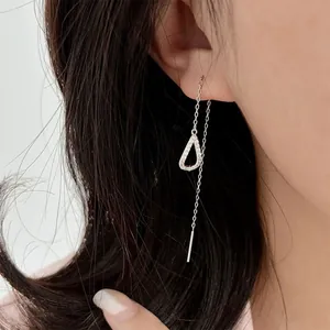 Close-up of silver heart drop threader earring with pavé zircon stones on a model