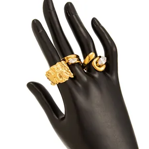 Detailansicht von drei vergoldeten Ringen mit Zirkonia auf einem schwarzen Hand-Display