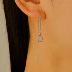 Close-up of a silver ear threader with a hollow teardrop pendant encrusted with crystals