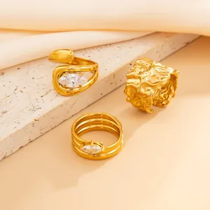 Macro detail of three irregular gold rings with marquise crystals on textured stone