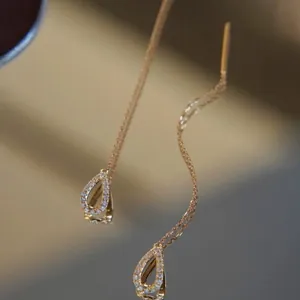 Detail of elegant gold teardrop threader earrings with shimmering pave-set crystals