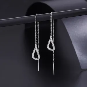Macro shot of silver heart drop earrings with white zircons on a black display stand