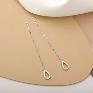 Detail of silver heart threader earrings with zircon teardrop charms on silk