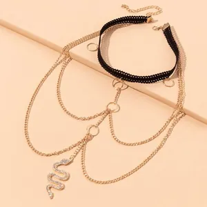 Detail van gelaagde gouden lichaamsketting met zwarte kant choker en slangenhanger