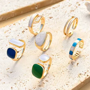 Detailed view of gold geometric rings with colorful enamel and zircon on stone surface