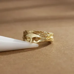 Détail macro de la bague visage de Vénus dorée avec texture martelée sur support