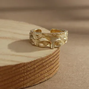 Gros plan d'une bague dorée avec relief visage de Vénus sur socle en bois