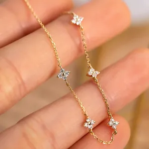 Detailed macro view of gold four-leaf clover bracelet with white zircons on hand