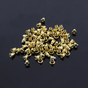 Bulk gold metal bullet clutch earring backs piled on a sleek black reflective background