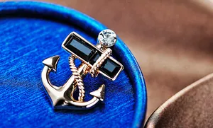 Close-up of golden anchor brooch with black gems and nautical rope texture detail