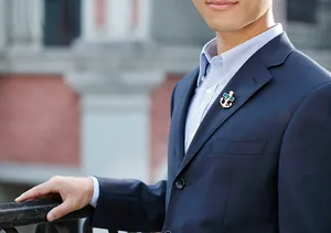 Close-up of golden anchor brooch with green gemstones on a classic navy blue suit lapel