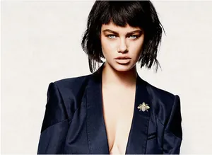 Detailed view of an exquisite gold bee brooch with pearls on a dark wool blazer lapel