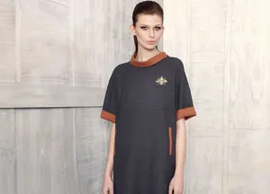Detail of grey short sleeve dress featuring contrast trim and a gold bee brooch accent