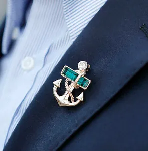 Nautical anchor brooch in gold with green emerald crystals on a navy suit lapel