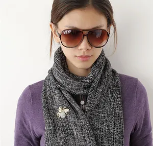 Detailed view of an exquisite crystal bee brooch pinned on a grey tweed scarf