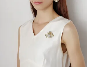 Exquisite gold-plated honey bee brooch with white rhinestones on white satin fabric