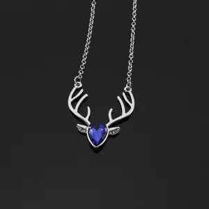 Macro shot of silver deer head pendant with deep blue teardrop gemstone on black background