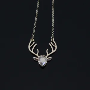 Detailed close-up of a gold deer head necklace featuring a pear-cut crystal pendant