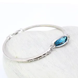 Dettaglio del bracciale argentato con cristallo blu ovale e accenti di zirconi