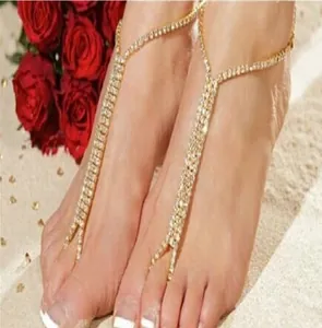 Detailed view of gold plated barefoot sandals with rows of sparkling crystals on beach