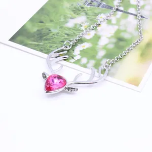 Detail of silver reindeer antler necklace featuring a vibrant pink heart-shaped crystal