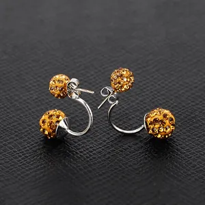 Dettaglio macro di orecchini a doppia sfera con pavé di strass oro ambra scintillanti
