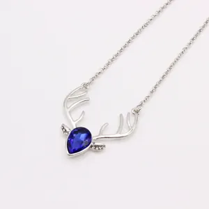Macro view of crystal deer head necklace pendant with blue teardrop gemstone and silver chain