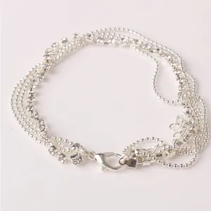 Multi-layer silver anklet with rhinestone chain and heart pendant on pink background