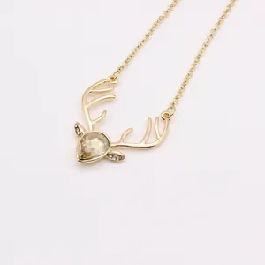 Close-up of golden reindeer pendant featuring a teardrop gemstone and micro-pave crystals
