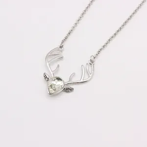 Macro view of silver deer pendant necklace featuring a heart-shaped crystal stone