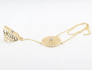 Macro detail of golden flower hand harness with hollow mandala pattern and crystal
