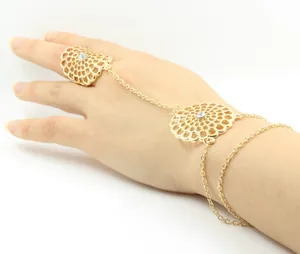 Detail of a gold hollow flower slave bracelet with rhinestones and ring-to-wrist chain
