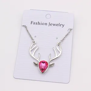 Close-up of silver deer antler necklace with a teardrop pink crystal on fashion card