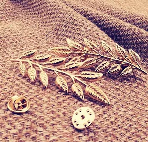 Close-up of golden leaf brooch with detailed veins and dual metal securing backs