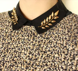 Macro shot of gold leaf branch collar pins on a shirt collar showing vein details