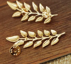 Close-up of golden leaf brooches featuring a textured brushed finish and pin back details