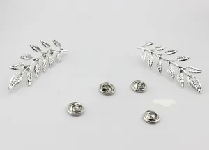 Detailed close-up of leaf-shaped silver metal brooches with textured veins and butterfly clasps