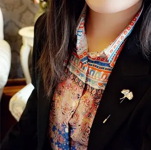 Golden ginkgo leaf brooch with detailed veins pinned on a black suit lapel